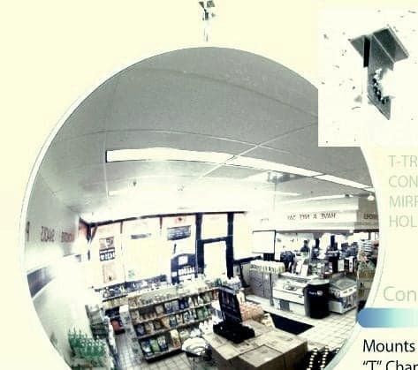 Indoor convex mirror hung from a drop ceiling T-bar in a convenience store showing the aisle and checkout counter