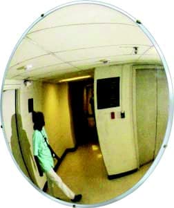 Convex mirror at a hospital corridor corner reflecting a staff member walking toward the intersection