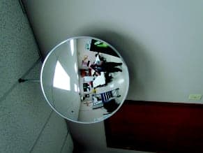 Indoor convex mirror mounted at an office hallway corner near a stairwell door